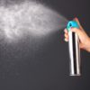 Sprayed air freshener in hand on grey background